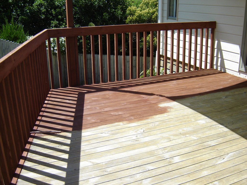 Raised wood deck with railing, half re-stained