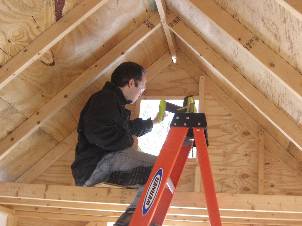 Carpenter on a ladder inside a framed gable end